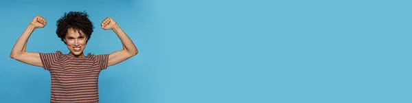Молода Кучерява Брюнетка Посміхається Робить Жест Переможця Ізольовано Синьому Фоні — стокове фото