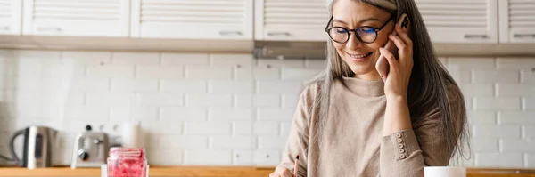 Modent Smilende Kvinne Som Snakker Mobiltelefon Mens Hun Jobber Kjøkkenet – stockfoto
