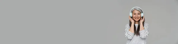 Зріла Білошкіра Жінка Посміхається Під Час Прослуховування Музики Навушниками Ізольовані — стокове фото