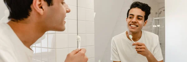 Sonriente Joven Hispano Cepillándose Los Dientes Espejo Del Baño —  Fotos de Stock