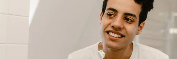 Sorrindo Jovem Hispânico Homem Escovar Dentes Espelho Banheiro — Fotografia de Stock