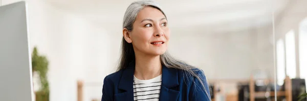 Gray Haired Asian Woman Sitting Blue Suit Table Looking Awayin — Stock Photo, Image