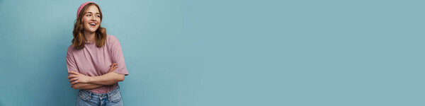 Молодая счастливая женщина улыбается и позирует перед камерой на синем фоне