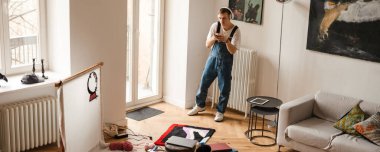 Genç beyaz adam cep telefonuyla fotoğraf çekiyor evde el halısı üzerinde çalışırken.