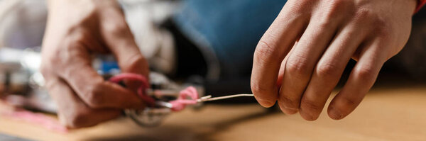 Young white man working with sewing machine indoors