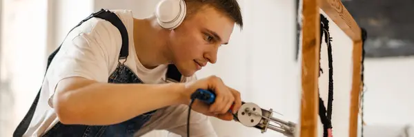 Kulaklıklı Genç Beyaz Adam Evde Dikiş Makinesiyle Halısı Üzerinde Çalışıyor — Stok fotoğraf