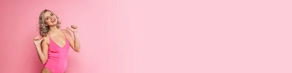 Портрет Улыбающейся Блондинки Купальнике Стоящей Фоне Розовой Стены Указывающей Пальцем — стоковое фото