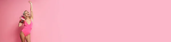 Молодая Блондинка Слушает Музыку Наушниками Держа Скейтборд Изолирован Розовом Фоне — стоковое фото