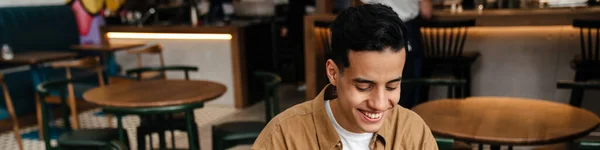 Junger Lächelnder Hispanischer Student Sitzt Cafétisch Mit Laptop Drinnen — Stockfoto