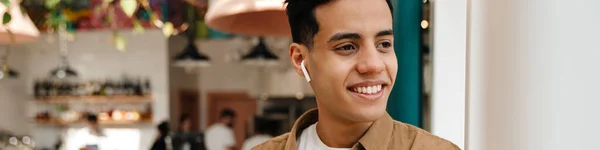 Улыбающийся Молодой Латиноамериканец Наушниках Видеозвонке Мобильного Телефона Стоящего Кафе Помещении — стоковое фото