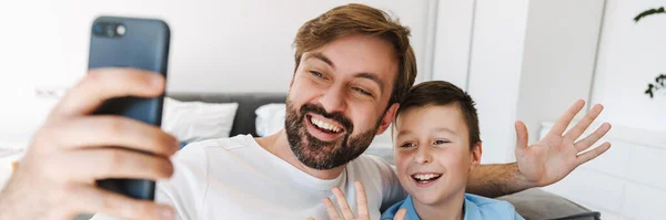 Szczęśliwy Ojciec Mały Syn Biorąc Selfie Pośrednictwem Smartfona Siedzi Kanapie — Zdjęcie stockowe