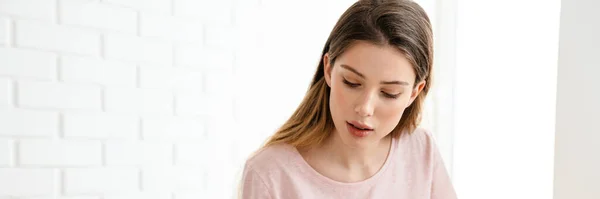 stock image Young white woman wearing lounge clothes sitting at the table with laptop computer, studying, using mobile phone