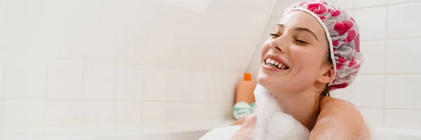 年轻的白人微笑女人在泡泡浴中放松 戴着浴帽 — 图库照片