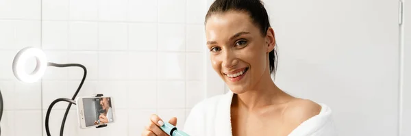 White Woman Smiling Using Mascara While Taking Footage Cellphone Home — Stock Photo, Image