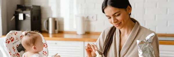 Jovem Morena Mãe Sorrindo Alimentando Seu Bebê Cozinha Casa — Fotografia de Stock