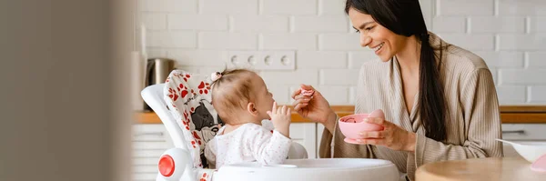 Joven Morena Madre Sonriendo Alimentando Bebé Cocina Casa —  Fotos de Stock