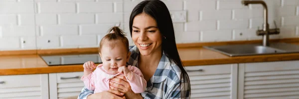 Joven Madre Sonriendo Sosteniendo Bebé Mientras Trabaja Con Ordenador Portátil —  Fotos de Stock