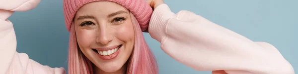 若いですホワイト女性とともにピンクの髪笑顔とポーズでカメラ隔離された上の青い壁 — ストック写真