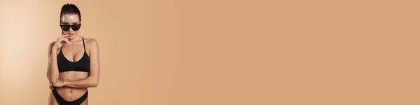 Молодая Брюнетка Купальниках Солнцезащитных Очках Смотрит Изолированный Бежевый Фон Камеры — стоковое фото