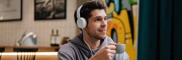 Χαμογελώντας Νεαρός Casual Άνθρωπος Ακουστικά Ακούγοντας Μουσική Κρατώντας Κινητό Τηλέφωνο — Φωτογραφία Αρχείου