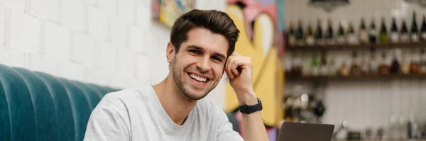 Hymyilevä Nuori Mies Opiskelija Istuu Kahvilassa Sisällä Kannettavan Tietokoneen Kanssa — kuvapankkivalokuva