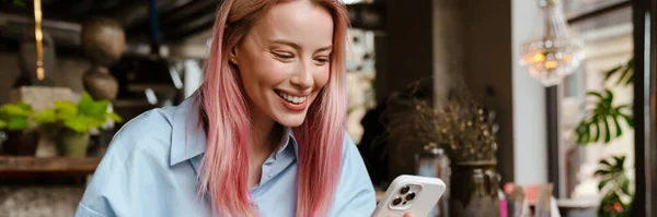 Молодая Улыбающаяся Женщина Пользуясь Мобильным Телефоном Пьет Кофе Кафе — стоковое фото