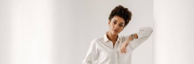 Young black woman leaning on wall and looking at camera indoors