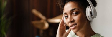 Young black woman listening music with headphones at home