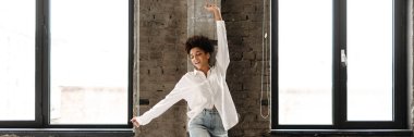 Young black woman in white shirt smiling and dancing indoors