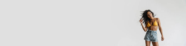 Black woman in swimsuit smiling and looking at camera isolated over white background