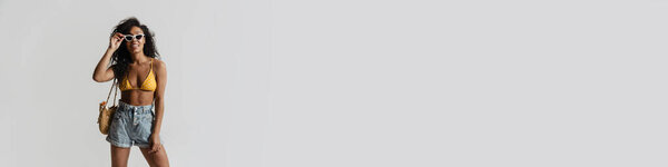 Black woman in swimsuit smiling while posing on camera isolated over white background