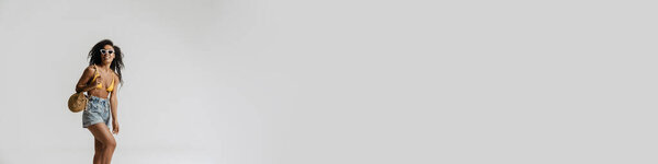 Черная женщина в купальнике улыбается, позируя перед камерой на белом фоне