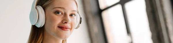 Jonge Blonde Vrouw Luisteren Muziek Met Koptelefoon Mobiele Telefoon Binnen — Stockfoto