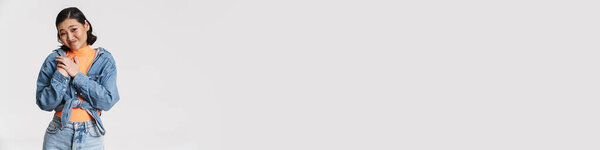 Молодая азиатская брюнетка женщина гримаса, держа руки на груди изолированы на белом фоне