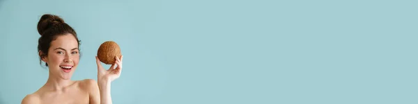 Pół Naga Brunetka Uśmiecha Się Podczas Pozowania Kokosa Izolowane Niebieskim — Zdjęcie stockowe