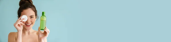 Напівгола Брюнетка Позує Бавовняною Подушечкою Лосьйоном Обличчя Ізольована Синьому Фоні — стокове фото