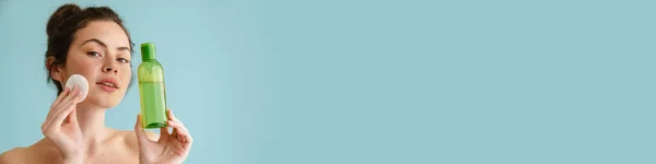 Полуобнаженная Брюнетка Позирует Хлопчатобумажным Блокнотом Лосьоном Лица Синем Фоне — стоковое фото