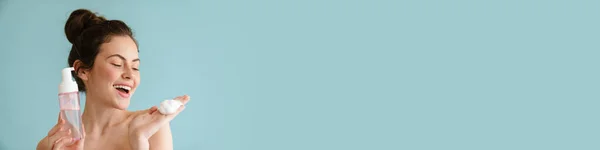 Полуобнаженная Брюнетка Улыбается Показывая Очищающую Пену Синем Фоне — стоковое фото
