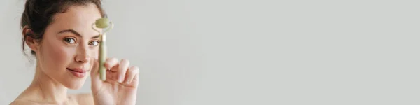 Полуобнаженная Брюнетка Улыбается Показывая Нефритовый Роллер Фоне — стоковое фото