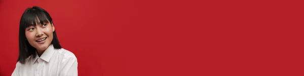 Молодая Азиатская Брюнетка Женщина Улыбаясь Глядя Сторону Изолированы Красном Фоне — стоковое фото