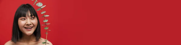 Азиатская Женщина Рубашки Смотрит Сторону Позируя Эвкалиптовым Изолированным Красном Фоне — стоковое фото