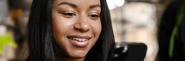 Schwarze Junge Frau Lächelt Und Benutzt Handy Während Sie Café — Stockfoto