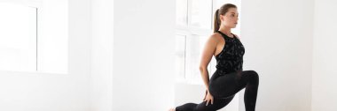 Genç beyaz kadın içeride yoga yaparken egzersiz yapıyor.