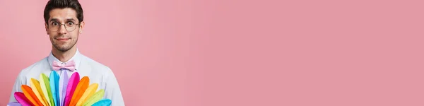 Nuori Yllättynyt Mies Yllään Rusetti Poseeraa Monivärinen Tuuletin Eristetty Vaaleanpunainen — kuvapankkivalokuva