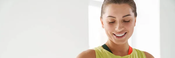 stock image Young white sportswoman looking at her smartwatch during practice indoors