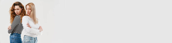 Молодые две женщины, стоящие спиной к спине после спора изолированы на белом фоне