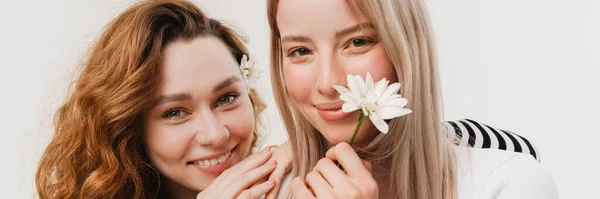 Nuori Valkoinen Kaksi Naista Halaus Hymyilevä Poseeratessaan Kukkia Eristetty Valkoisella — kuvapankkivalokuva
