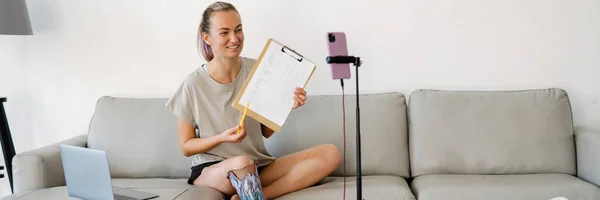 Hymyilevä Nuori Valkoinen Vammainen Nainen Bloggaaja Proteettinen Jalka Istuu Sohvalla — kuvapankkivalokuva