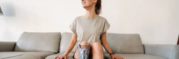 Gülümseyen Sakat Protez Bacaklı Bir Kadın Evdeki Kanepede Oturuyor — Stok fotoğraf