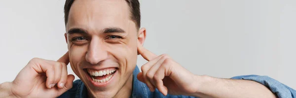 Νεαρός Μελαχρινός Άντρας Χαμογελάει Και Ακουμπάει Αυτιά Του Απομονωμένα Λευκό — Φωτογραφία Αρχείου